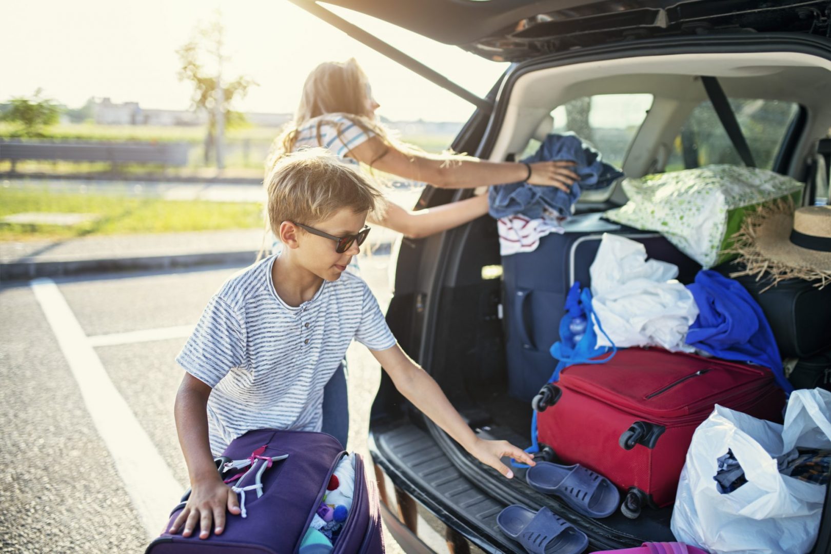 Kids Helping To Pack The Family Car For Road Trip.