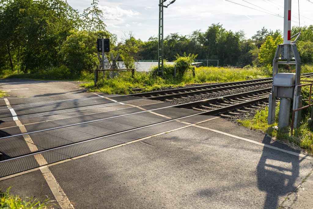 Empty Railroad Crossing In The Countryside, On The Road With Open Barriers.